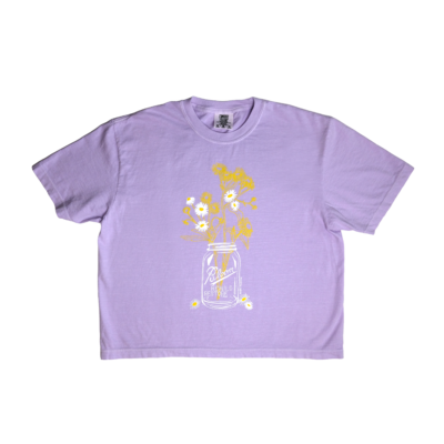 Bloom t-shirt – lavendar colored boxy crop tee, with mason jar holding daisy fleabane wildflowers. Mason jar says 'Bloom' and underneath it 'RESTORE REWILD'.